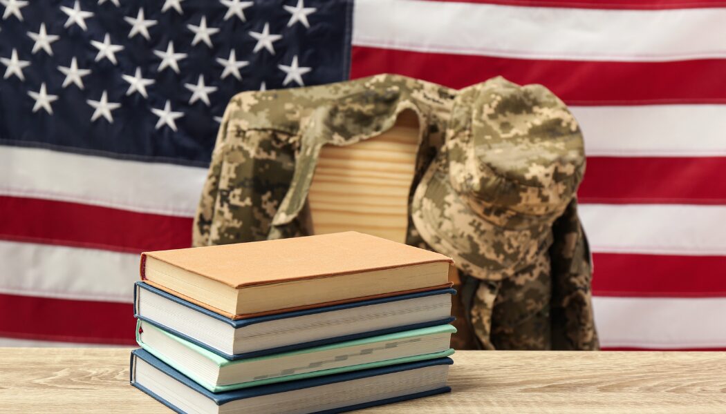 Chair, books, soldier uniform and USA flag near light textured wall. Military education concept